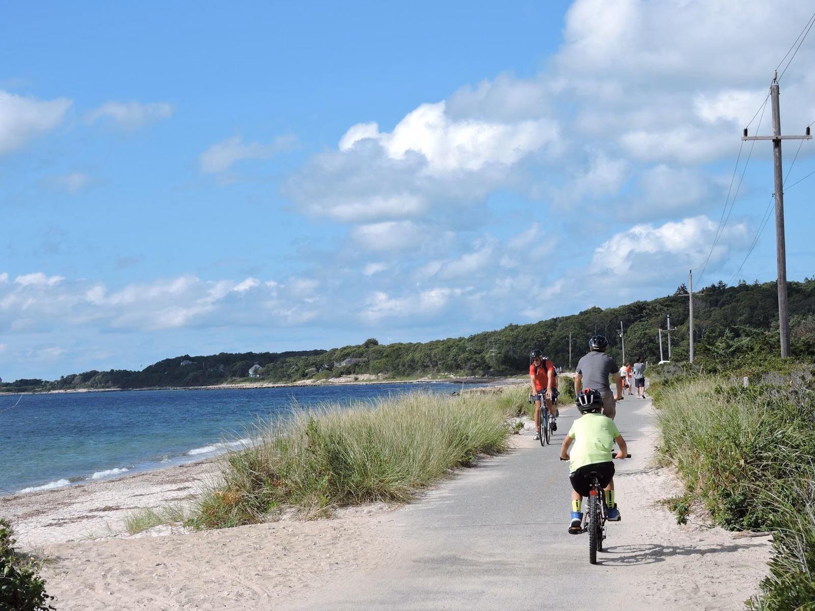 Cyclists riding the Shining Sea Bikeway in Falmouth beside a sandy beach and the water, August 2014